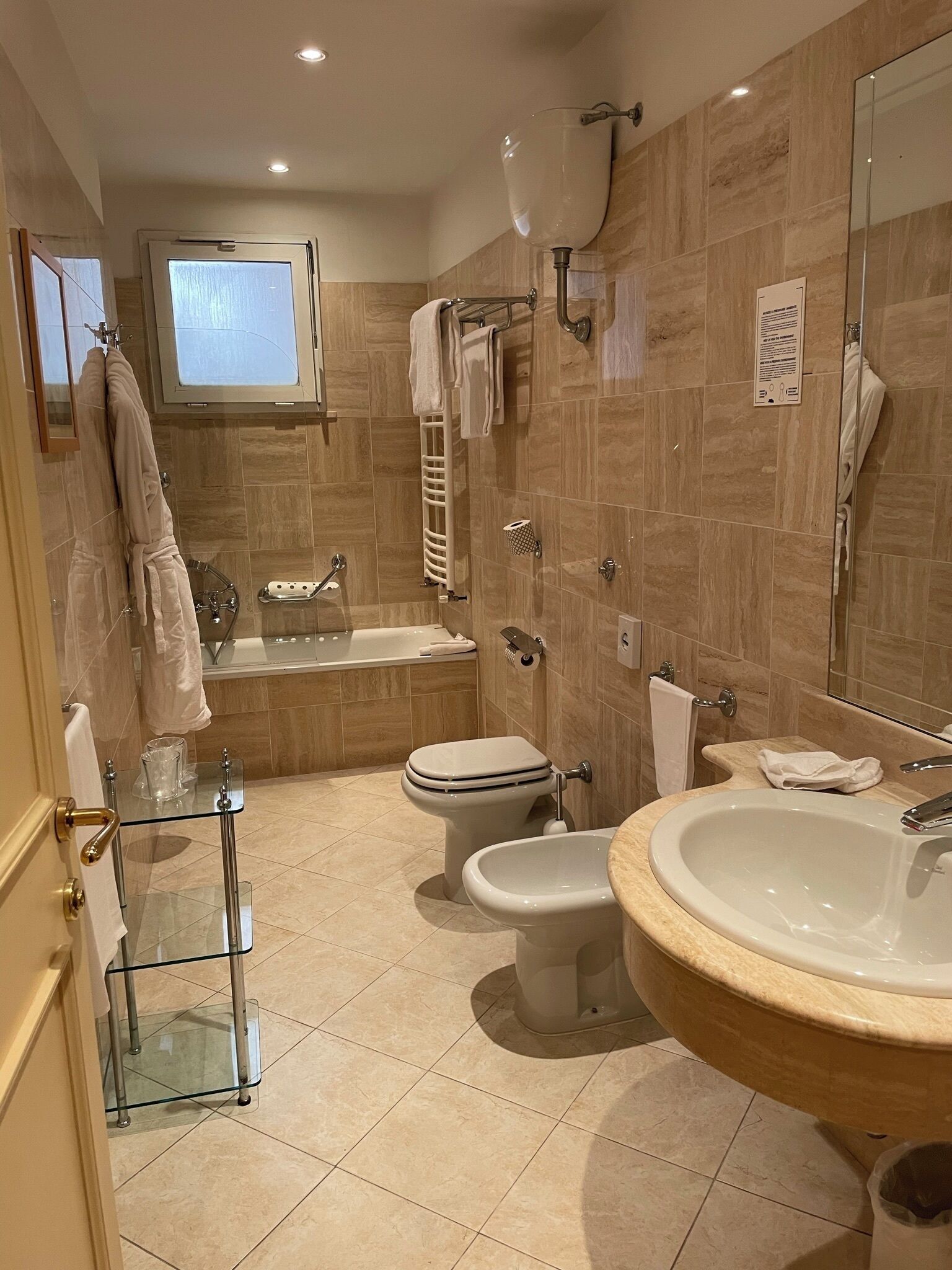 Un bagno moderno con box doccia in vetro, una vasca da bagno freestanding, un bidet e un lavandino grande.