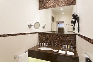 A bathroom with a sink, mirror, towel rack, and a hairdryer mounted on the wall.
