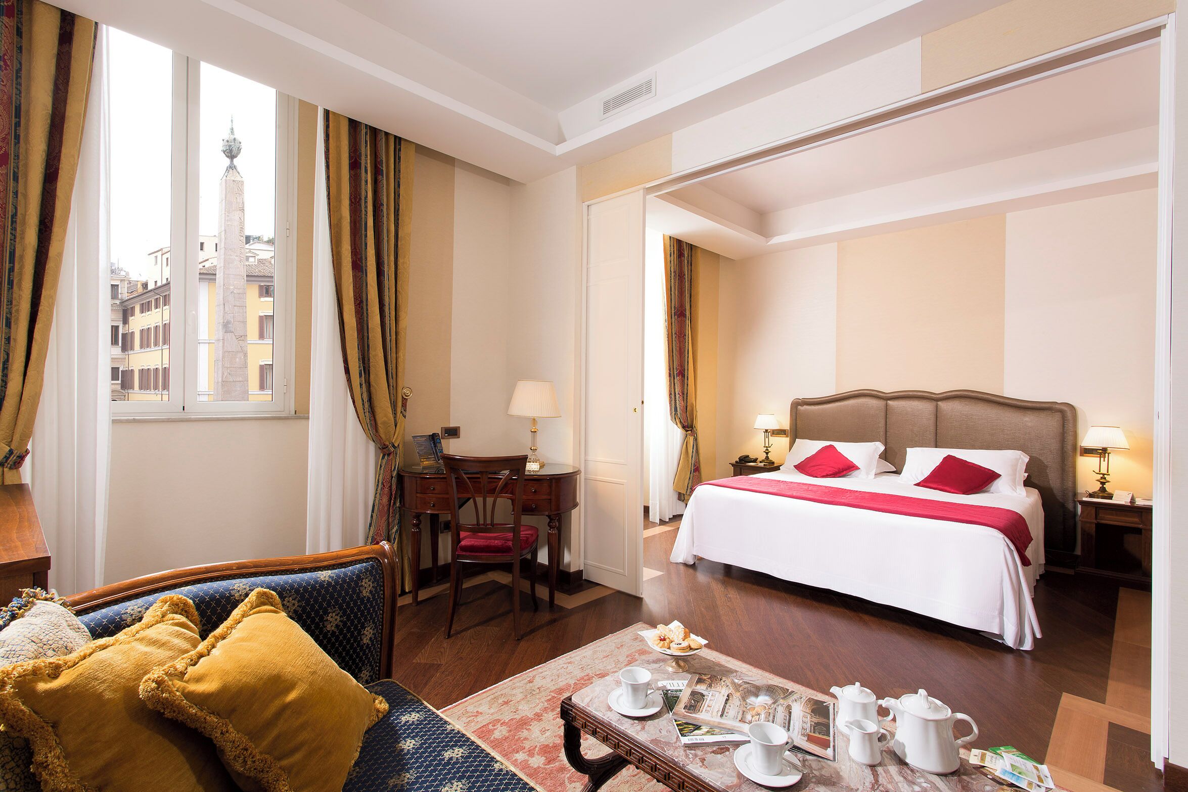 Habitación de hotel con cama, escritorio, silla, sofá y mesa de comedor con juego de té.