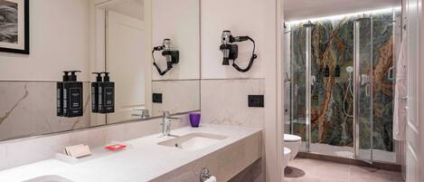 A modern bathroom with two sinks, a large mirror, and a shower area with a glass door.