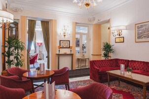 A hotel lobby with a red sofa, a wooden coffee table, and a red armchair.