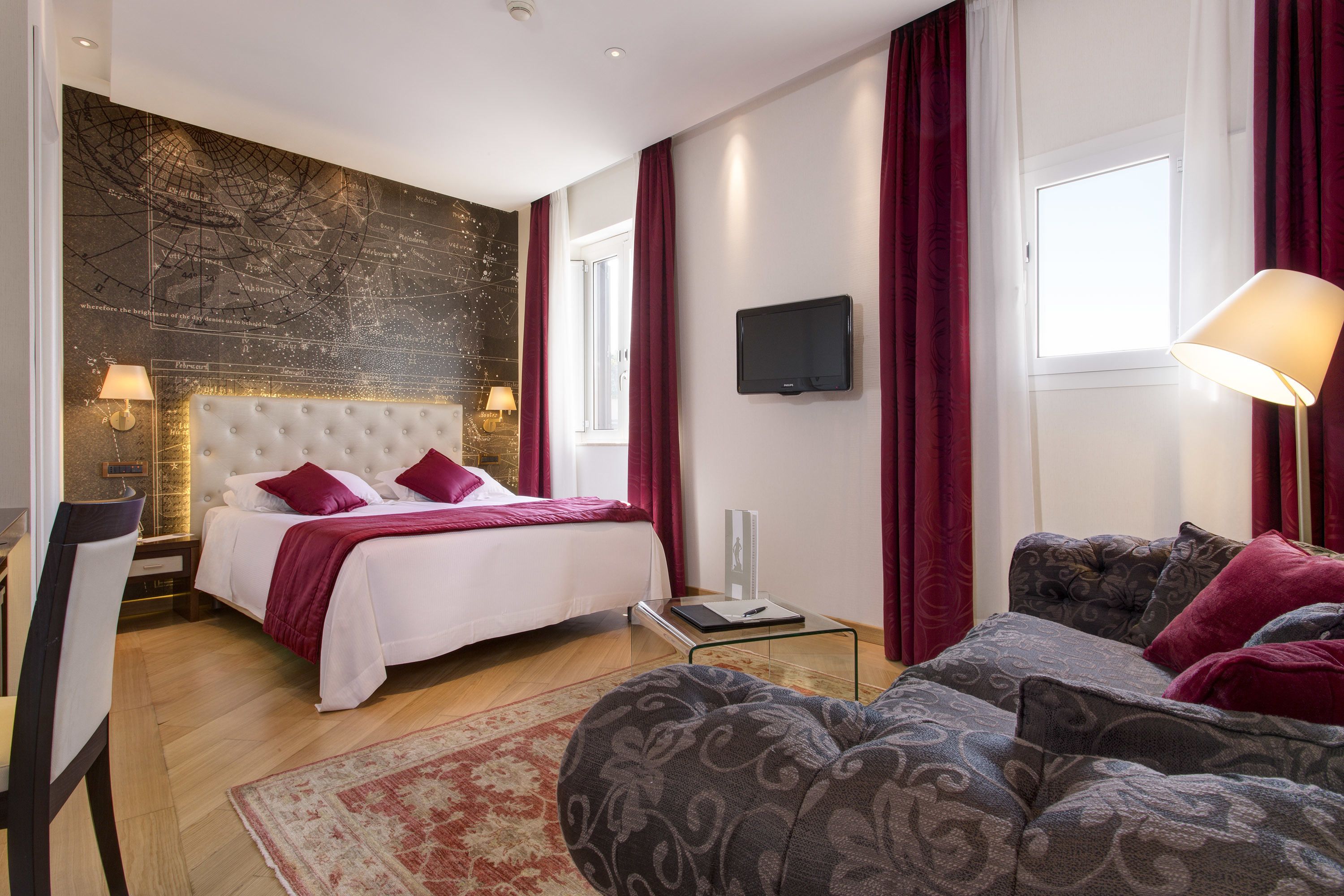A bedroom with a large bed, a sofa, a TV, and a wall with a map.