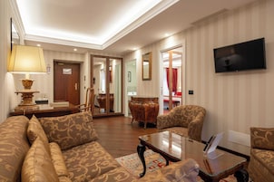 A spacious living room with a sofa, armchairs, a coffee table, and a television.