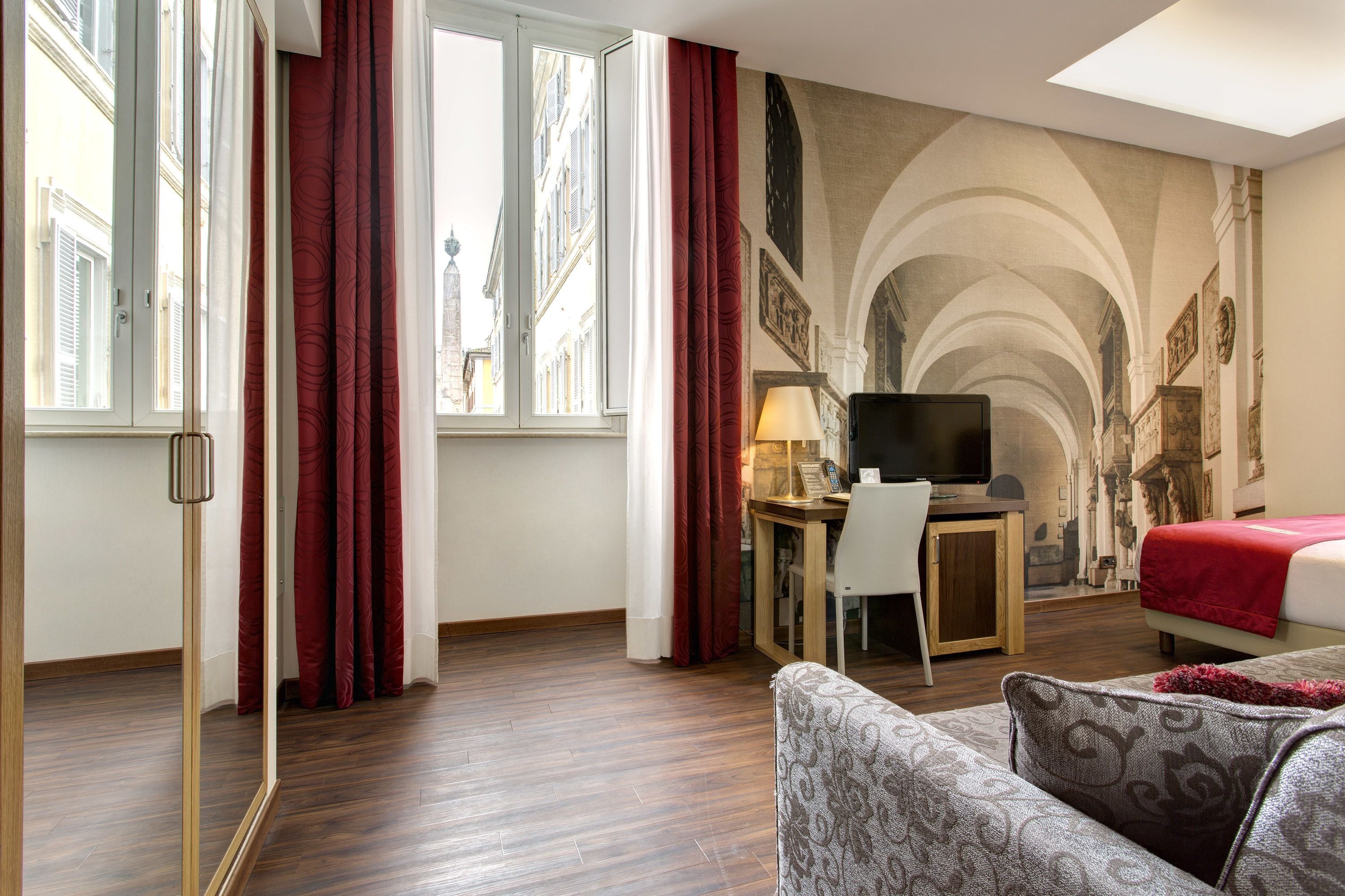 A hotel room with a bed, a desk with a computer, a TV, and a couch.