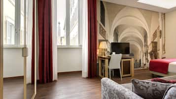 A hotel room with a bed, a desk with a computer, a TV, and a couch.