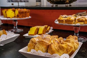 A buffet with various baked goods including pastries and cakes.