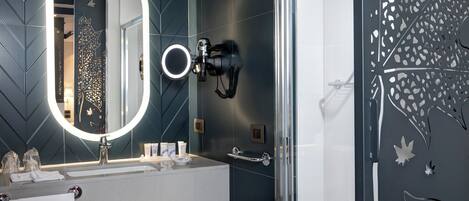 A modern bathroom with a large mirror, a shower enclosure, and decorative wall panels.