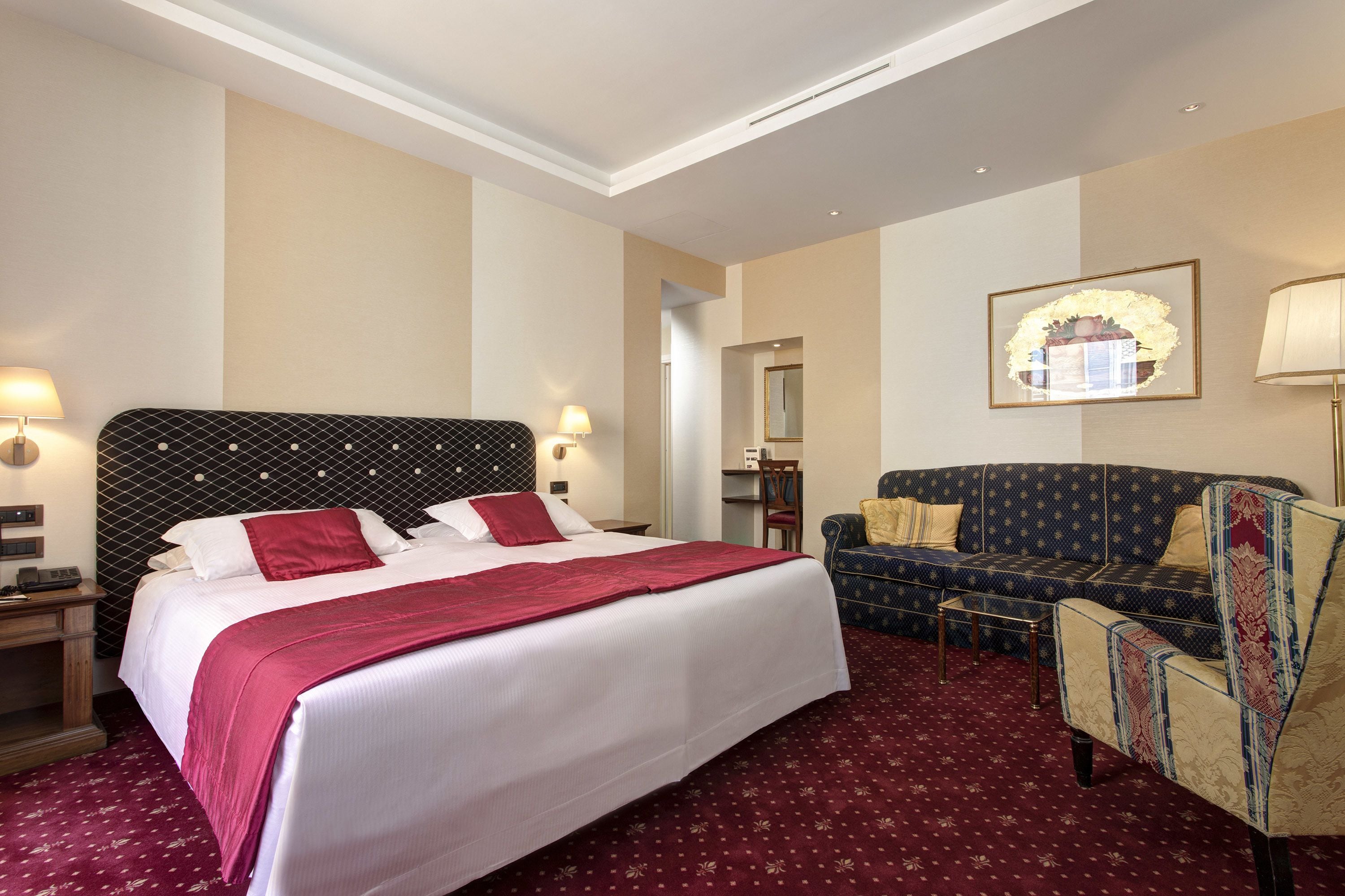 Une chambre d’hôtel avec un grand lit, un canapé, un fauteuil et un bureau.