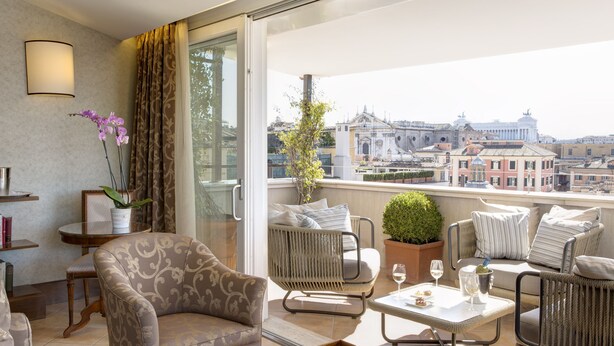 A balcony with a sofa, chairs, a table, and a potted plant. - Hotel Nazionale (Rome)