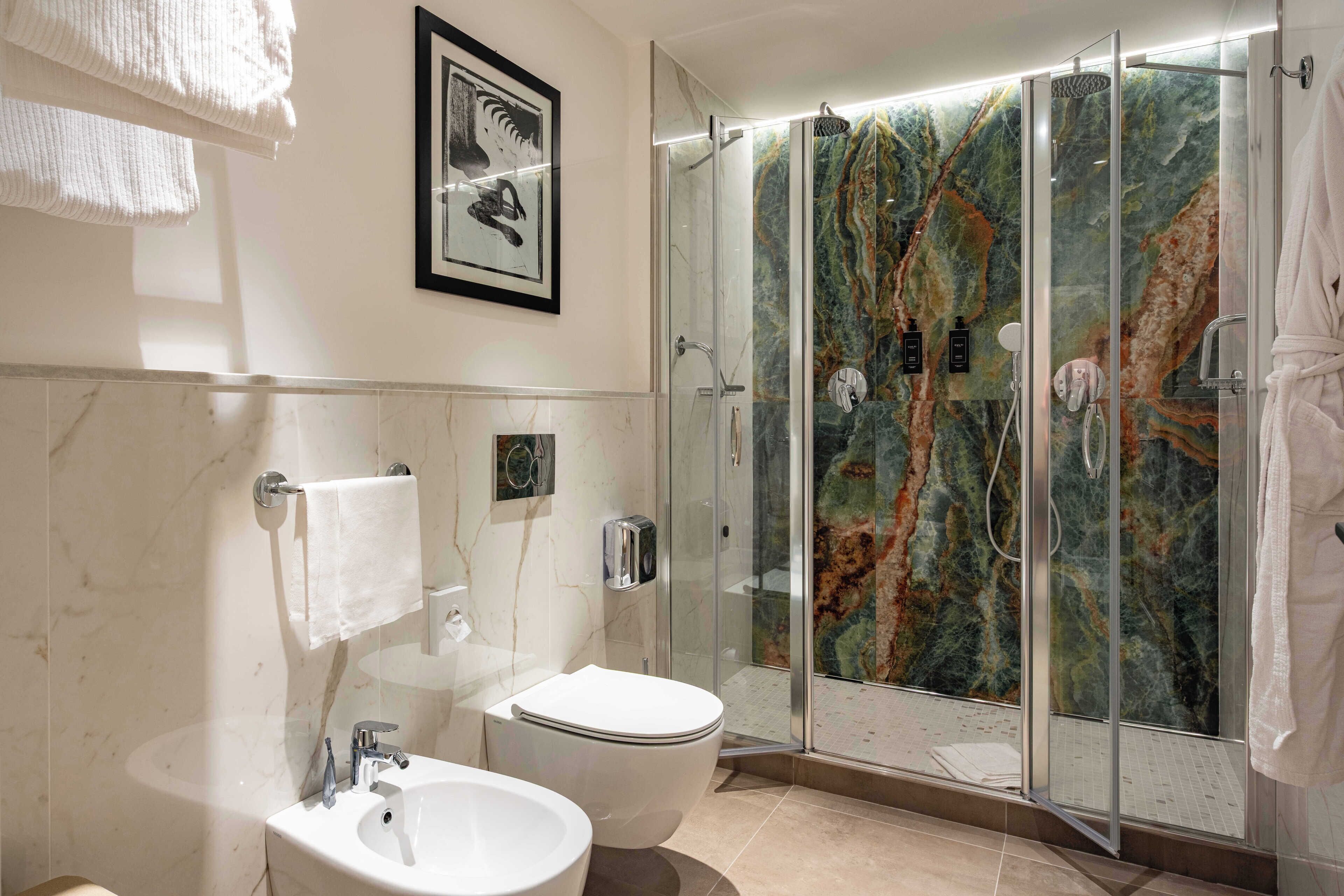 A modern bathroom with a glass-enclosed shower, a white sink, and a toilet.