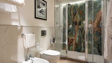 A modern bathroom with a glass-enclosed shower, a white sink, and a toilet.