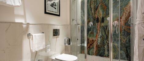 A modern bathroom with a glass-enclosed shower, a white sink, and a toilet.