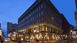 Ett hotell med flera våningar, en böjd fasad, stora fönster och en balkong på andra våningen.