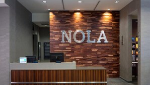 En receptionsdisk med en väggpanel i trä och bokstäverna ”NOLA” upplysta.