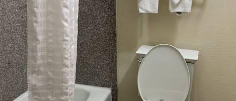 A bathroom with a bathtub, toilet, and a towel rack with towels.