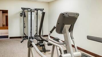 A gym with exercise equipment including a treadmill, elliptical, and weight machines.