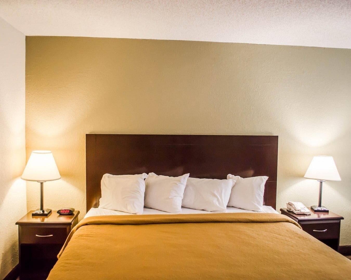 A hotel room with a bed, two bedside tables, and lamps.