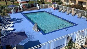 A rectangular pool with a blue deck, surrounded by white railings. There are lounge chairs and umbrellas around the pool. - Quality Inn & Suites Pensacola Bayview (Pensacola)