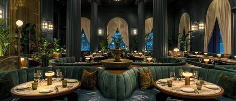 A luxurious dining area with green upholstered booths, round tables, and a central fountain.