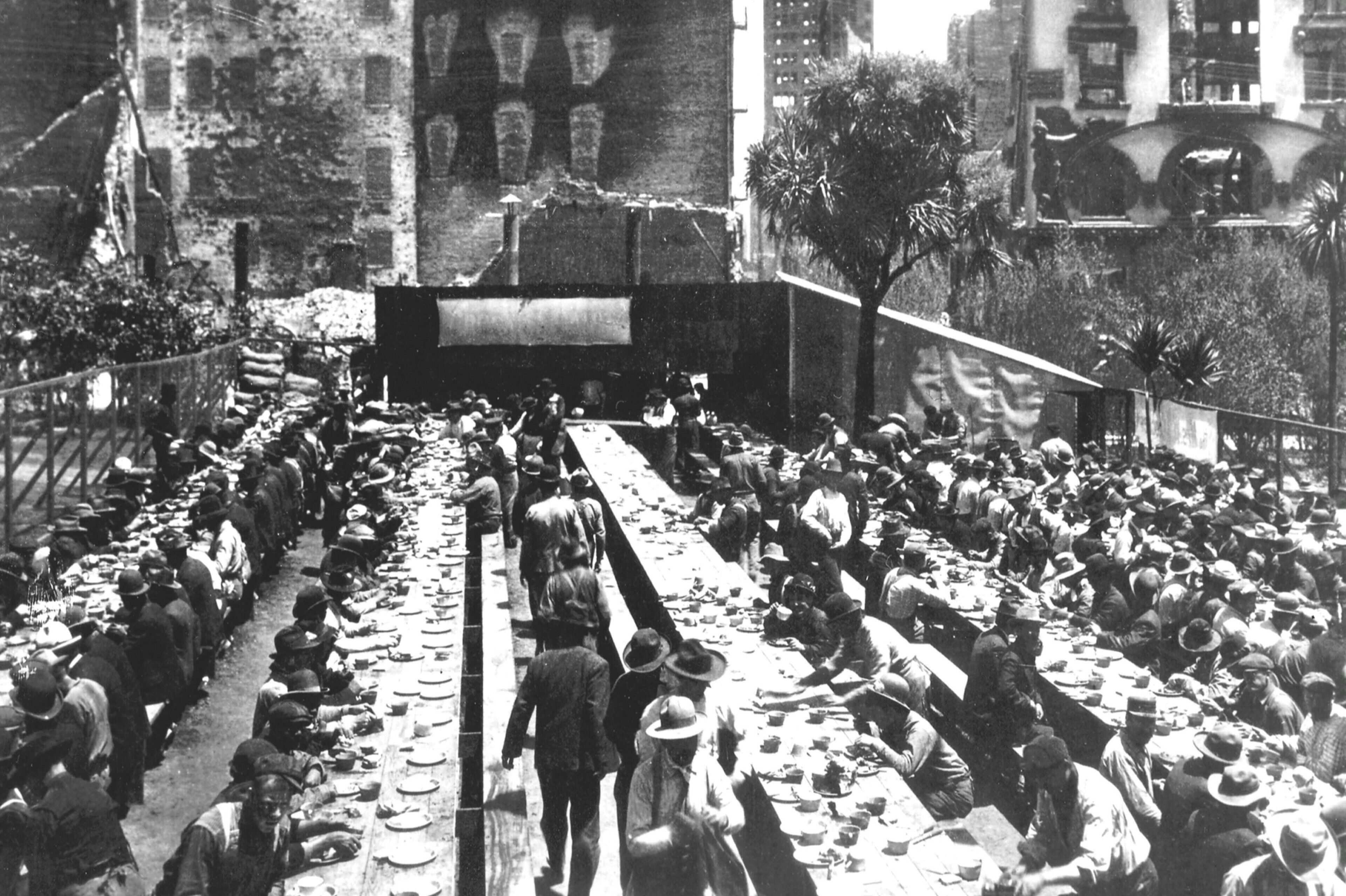 A crowded outdoor dining area with long tables and people seated.