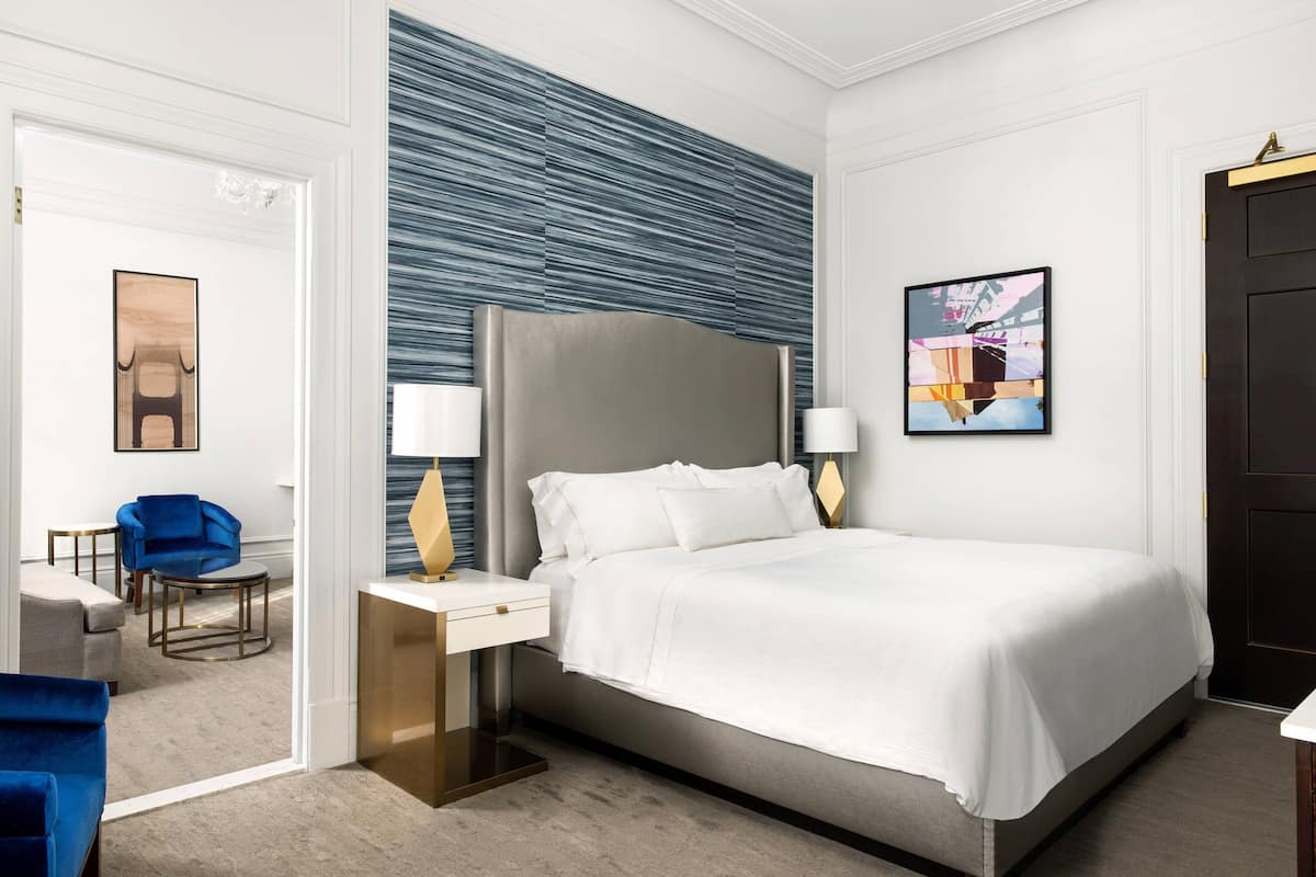 Een moderne hotelkamer met een groot bed, een nachtkastje, een blauwe stoel en een wand met een structuurontwerp.