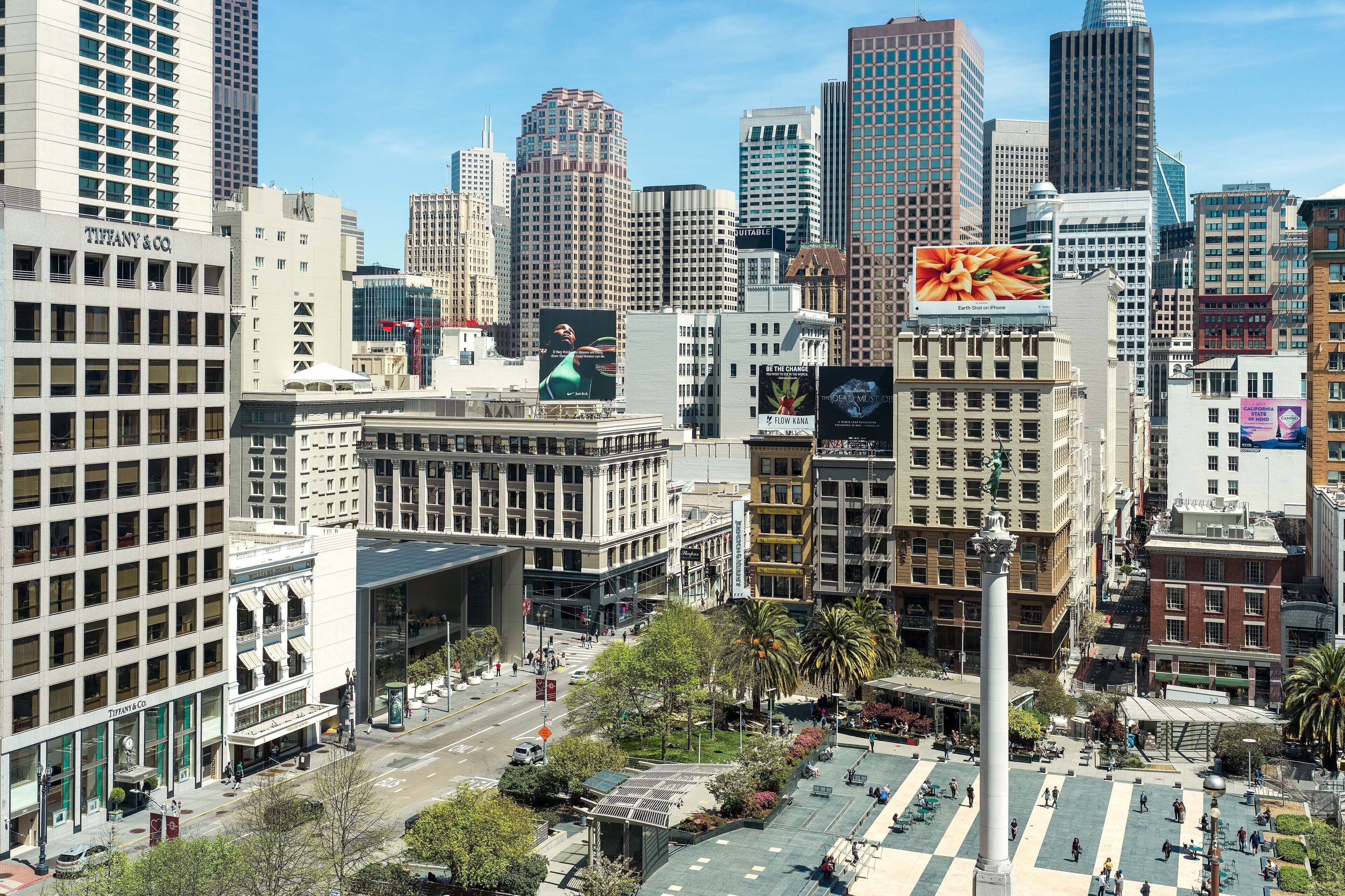 A cityscape with modern high-rise buildings, a prominent Tiffany & Co. store, and a large billboard.