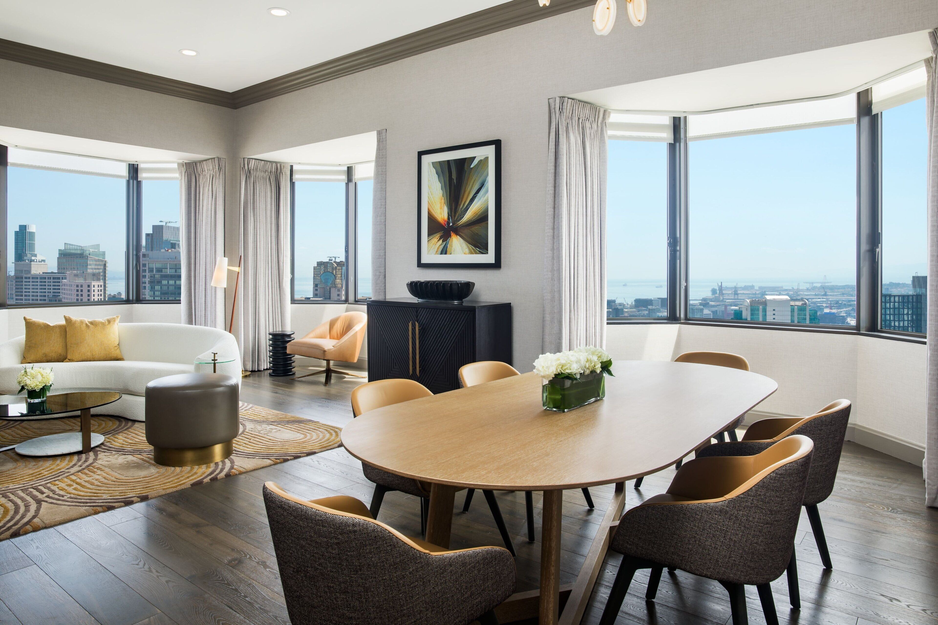 Ein modernes Wohnzimmer mit Essbereich, großen Fenstern und Blick auf die Stadt.