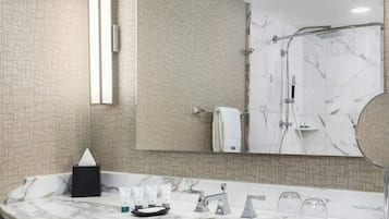 A modern bathroom with a marble sink, a large mirror, and a shower area.