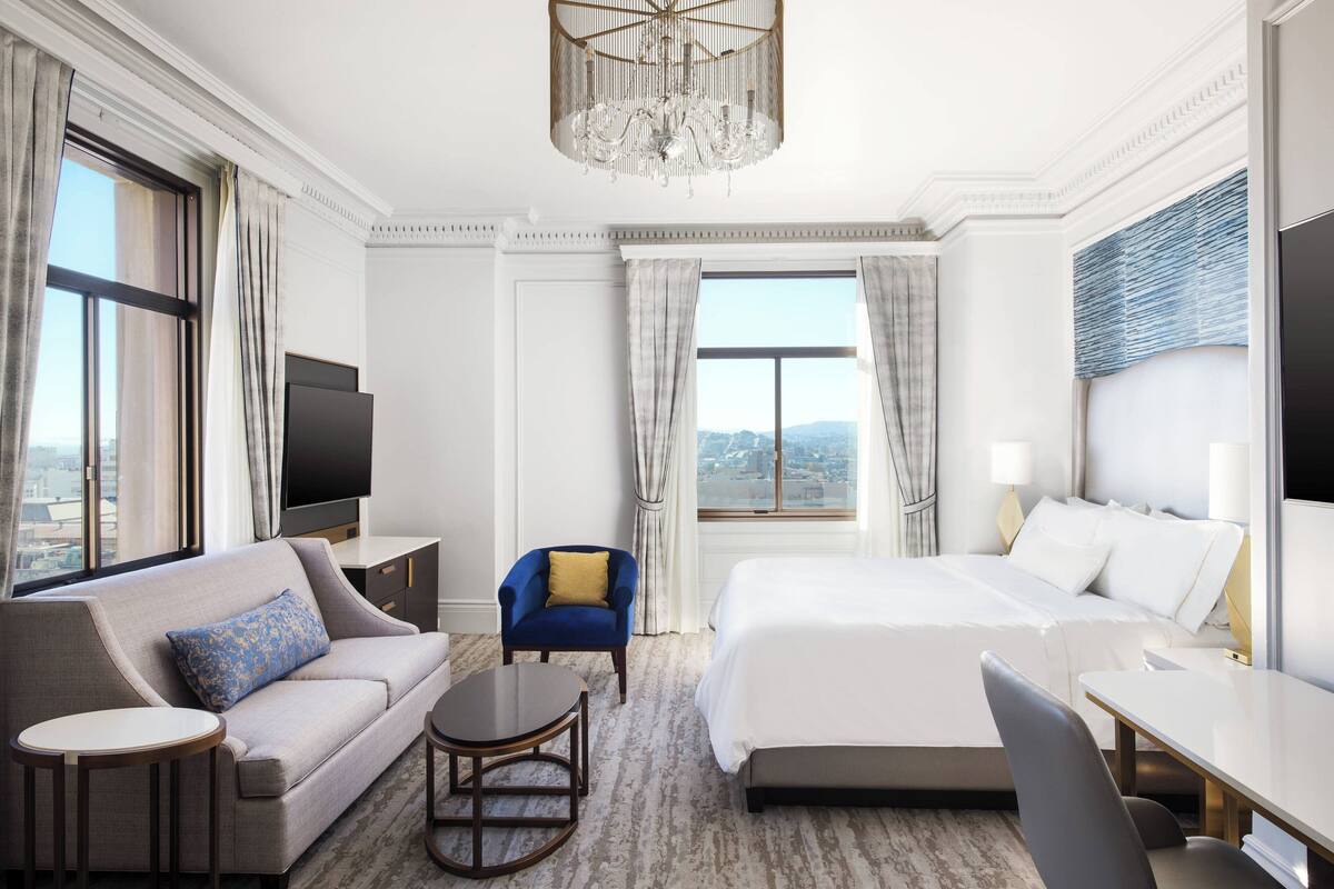Een hotelkamer met een groot bed, een bank, een televisie, een bureau en een stoel.