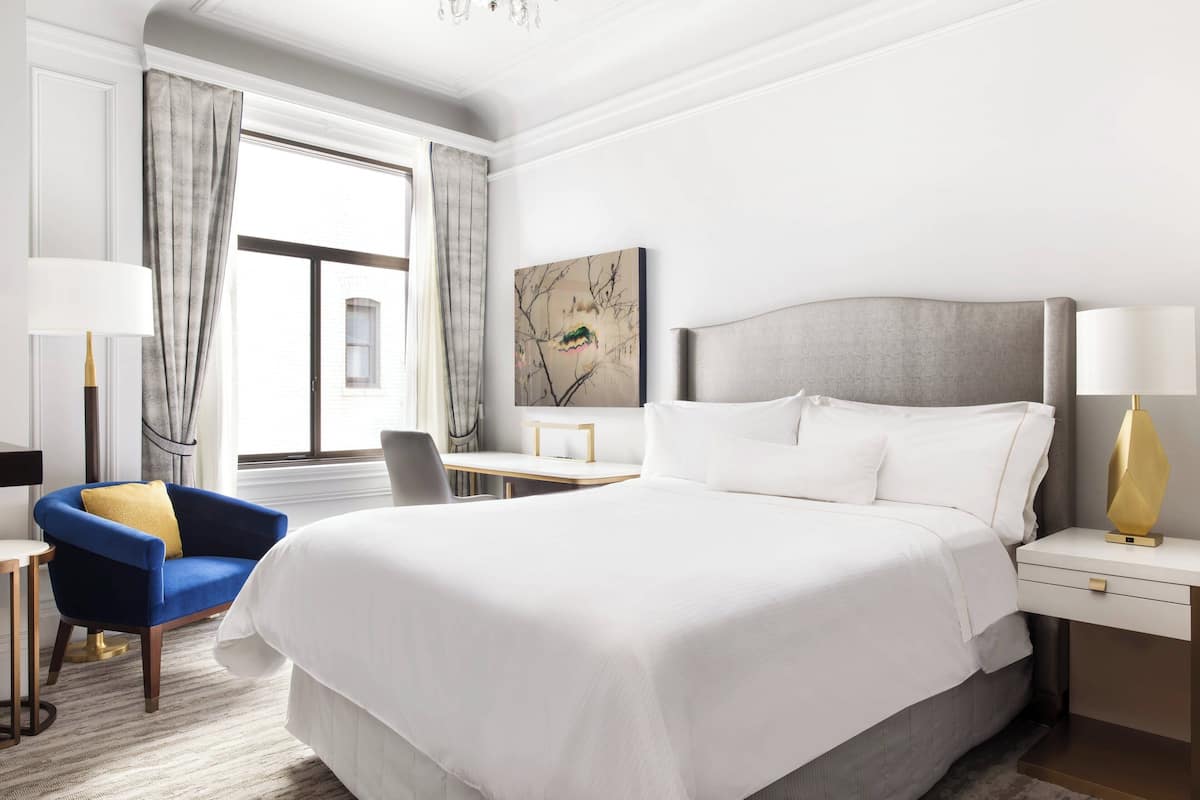 Een hotelkamer met een groot bed, een bureau, een stoel en een lamp.