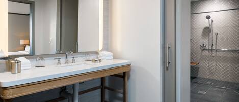 A modern bathroom with a large mirror, two sinks, and a shower area.