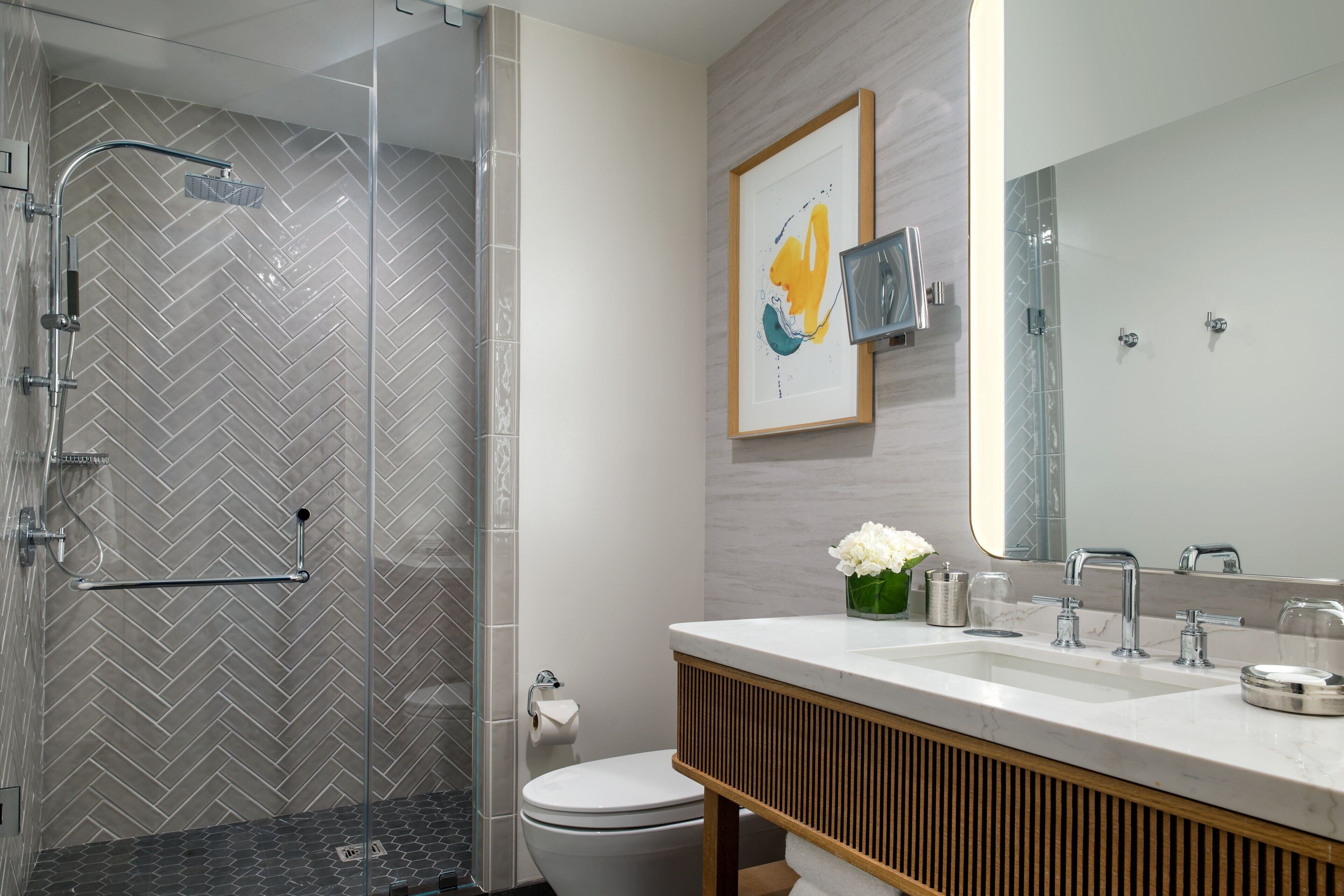 A modern bathroom with a glass-enclosed shower, a white toilet, and a vanity with a mirror.