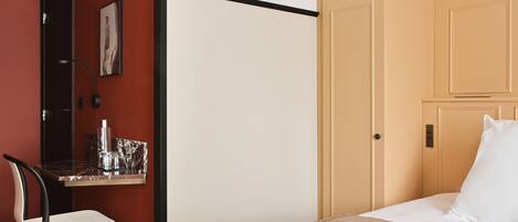 A hotel room with a bed, a desk with a chair, and a wardrobe.