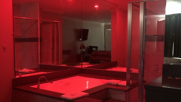 Un baño moderno con un espejo grande, una bañera y una zona de ducha.