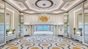 A spacious hotel lobby with a patterned carpet, a large chandelier, and a view through the glass doors.