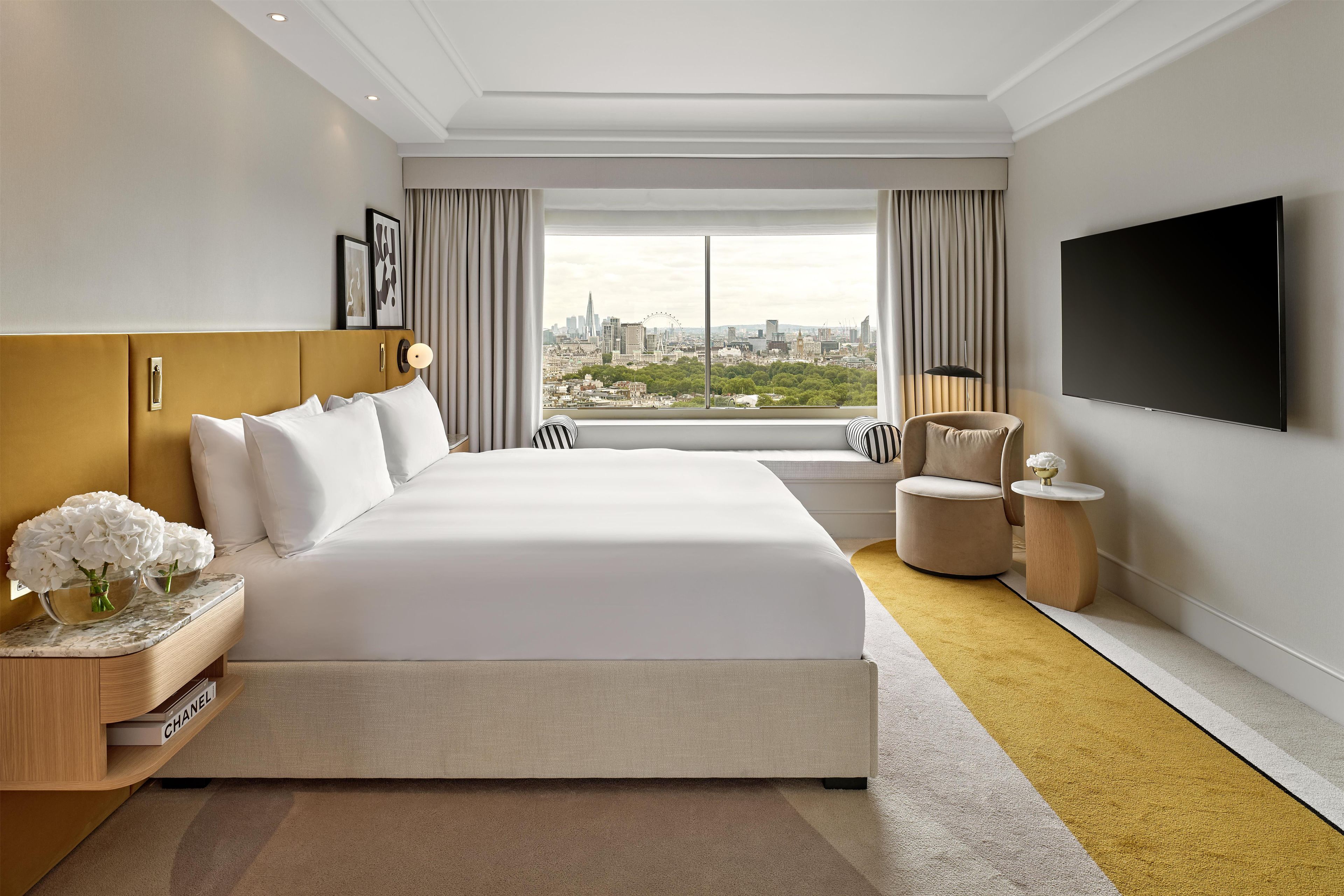 Une chambre d’hôtel moderne dotée d’un grand lit, d’une vue sur la ville, d’un téléviseur à écran plat et d’une petite table d’appoint.