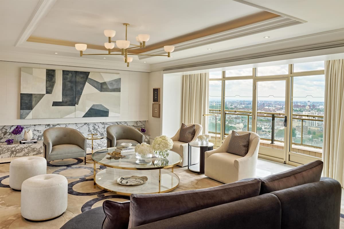 Ett modernt vardagsrum med utsikt över staden, en stor abstrakt målning och en kristallkrona.