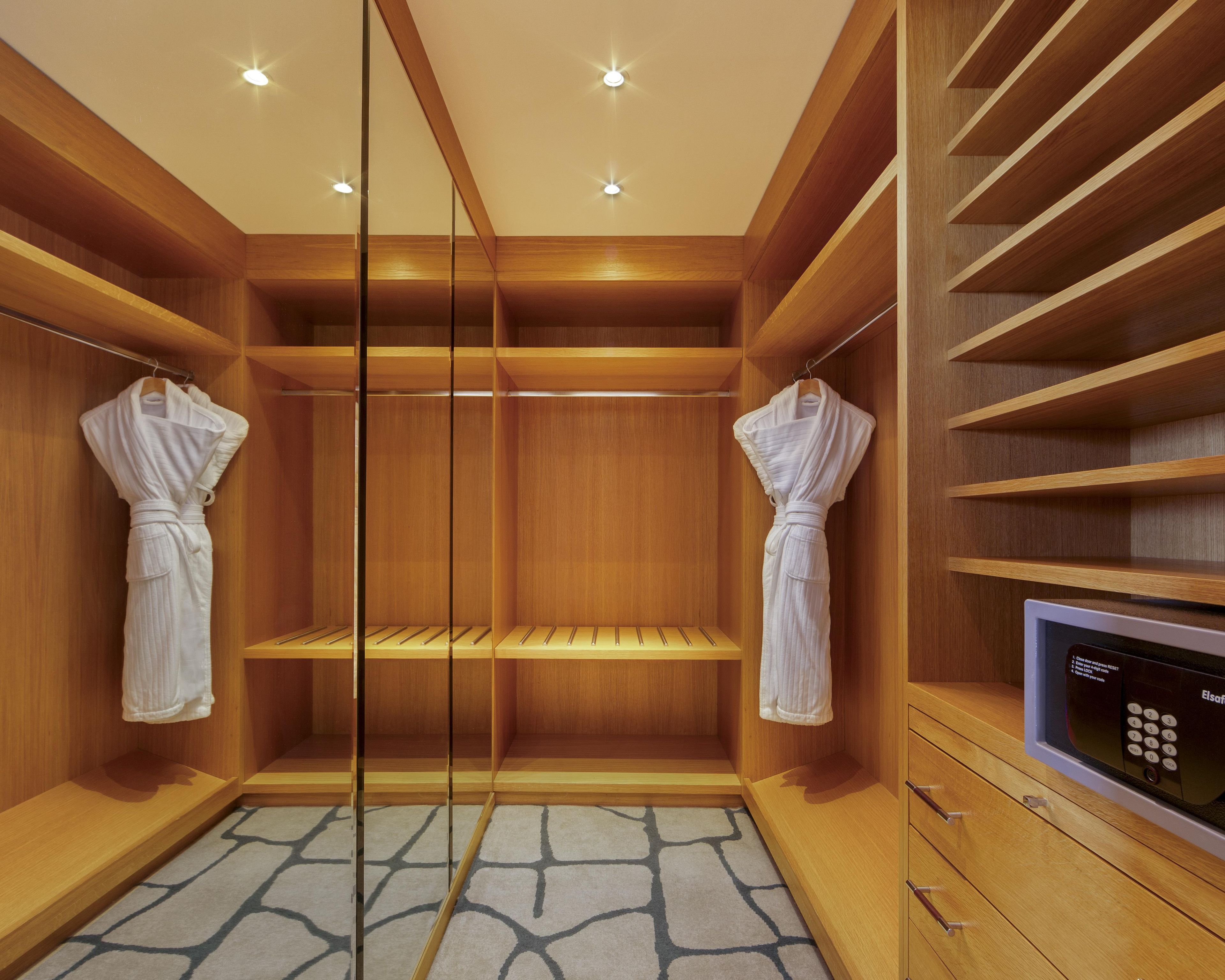 Ein begehbarer Kleiderschrank mit Holzregalen, einer eingebauten Mikrowelle und einem gemusterten Teppich.