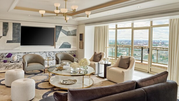 A modern living room with a large TV, comfortable seating, a coffee table, and a city view. - London Hilton on Park Lane (London)