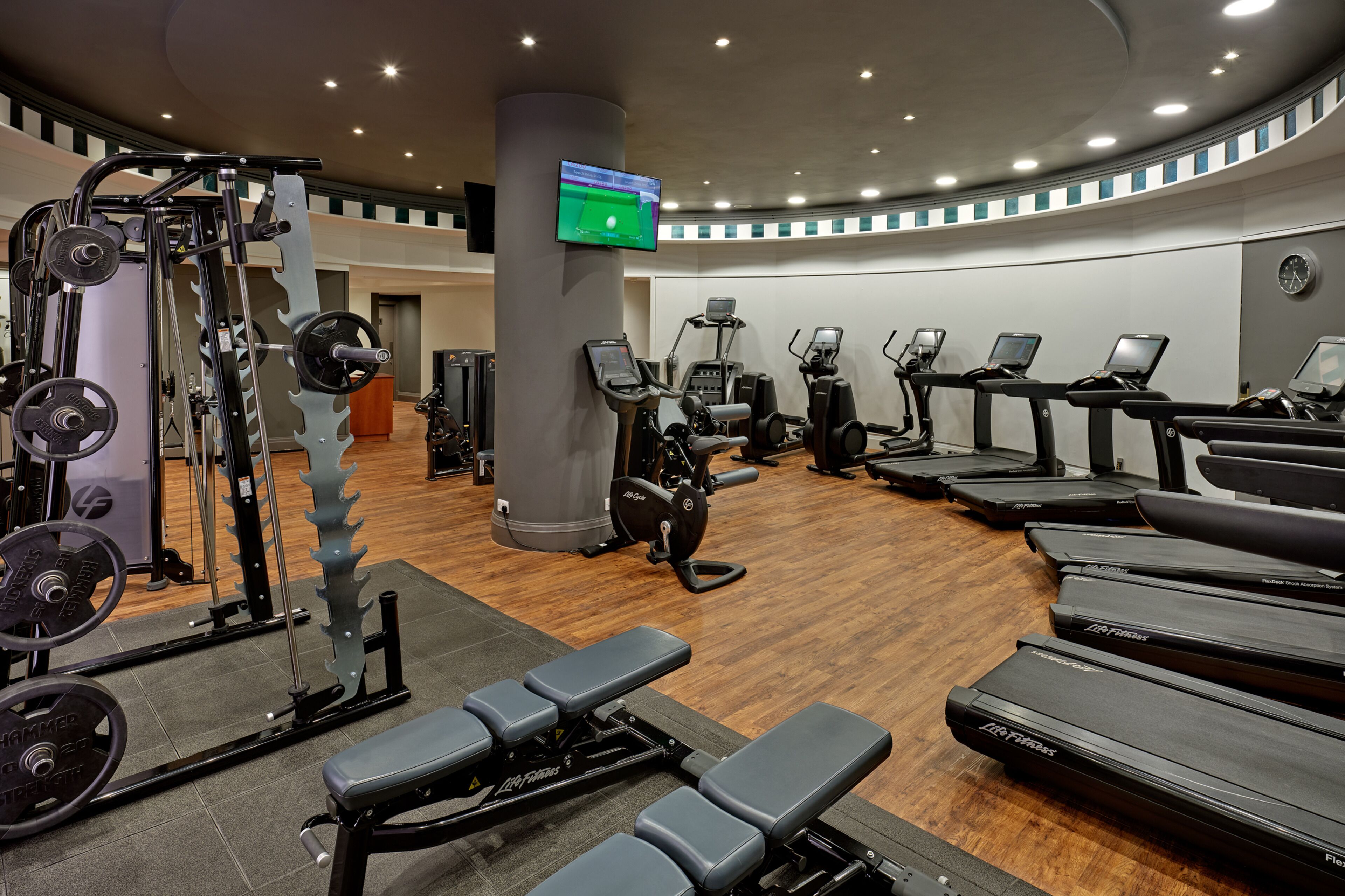 A gym with various exercise equipment, including treadmills, weight machines, and a rowing machine.