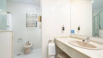 Un bany amb un lavabo de marbre, un bidet, una barra de tovalloles i un mirall.