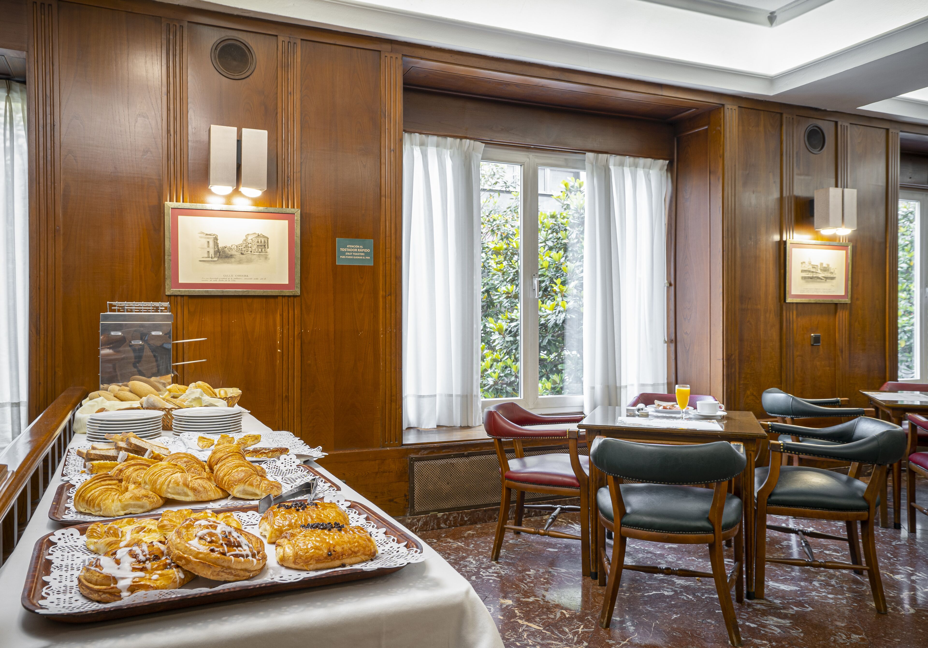 A breakfast buffet with pastries and a dining area with chairs and tables.