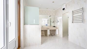 A modern bathroom with a large mirror, a towel rack, and a shower area.