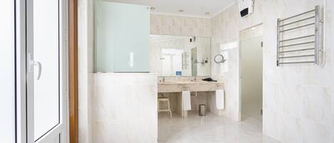 A modern bathroom with a large mirror, a towel rack, and a shower area.