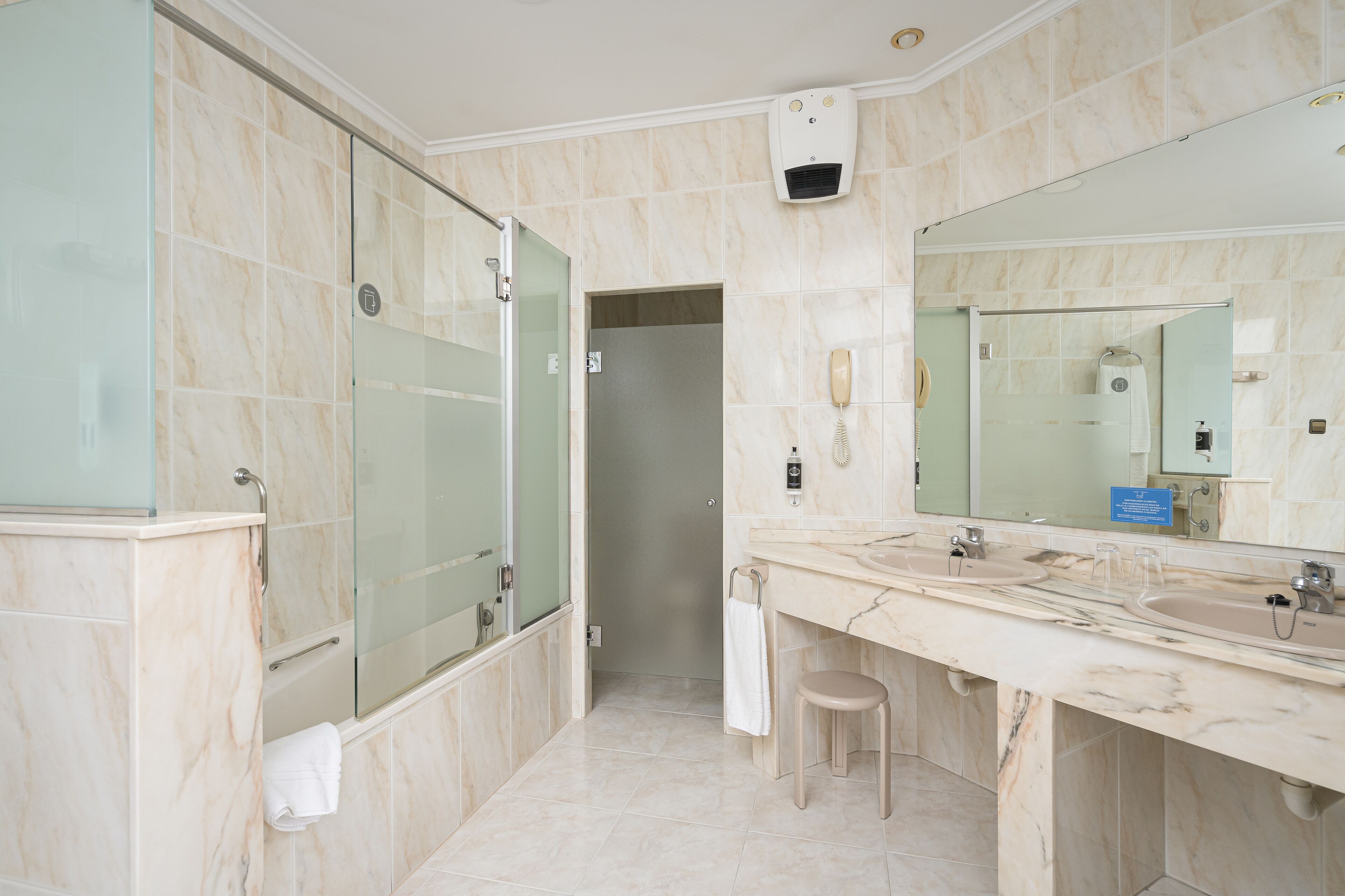 A modern bathroom with a glass shower enclosure, a vanity with two sinks, and a large mirror.