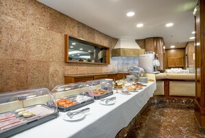Una mesa de buffet con diversos alimentos y cubiertos.