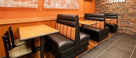A Subway restaurant interior with booths, tables, and a stone wall with the Subway logo.