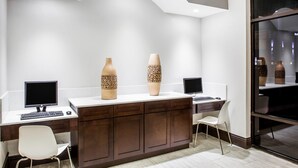Un espacio de oficina moderno con dos escritorios, dos sillas y dos grandes jarrones decorativos.