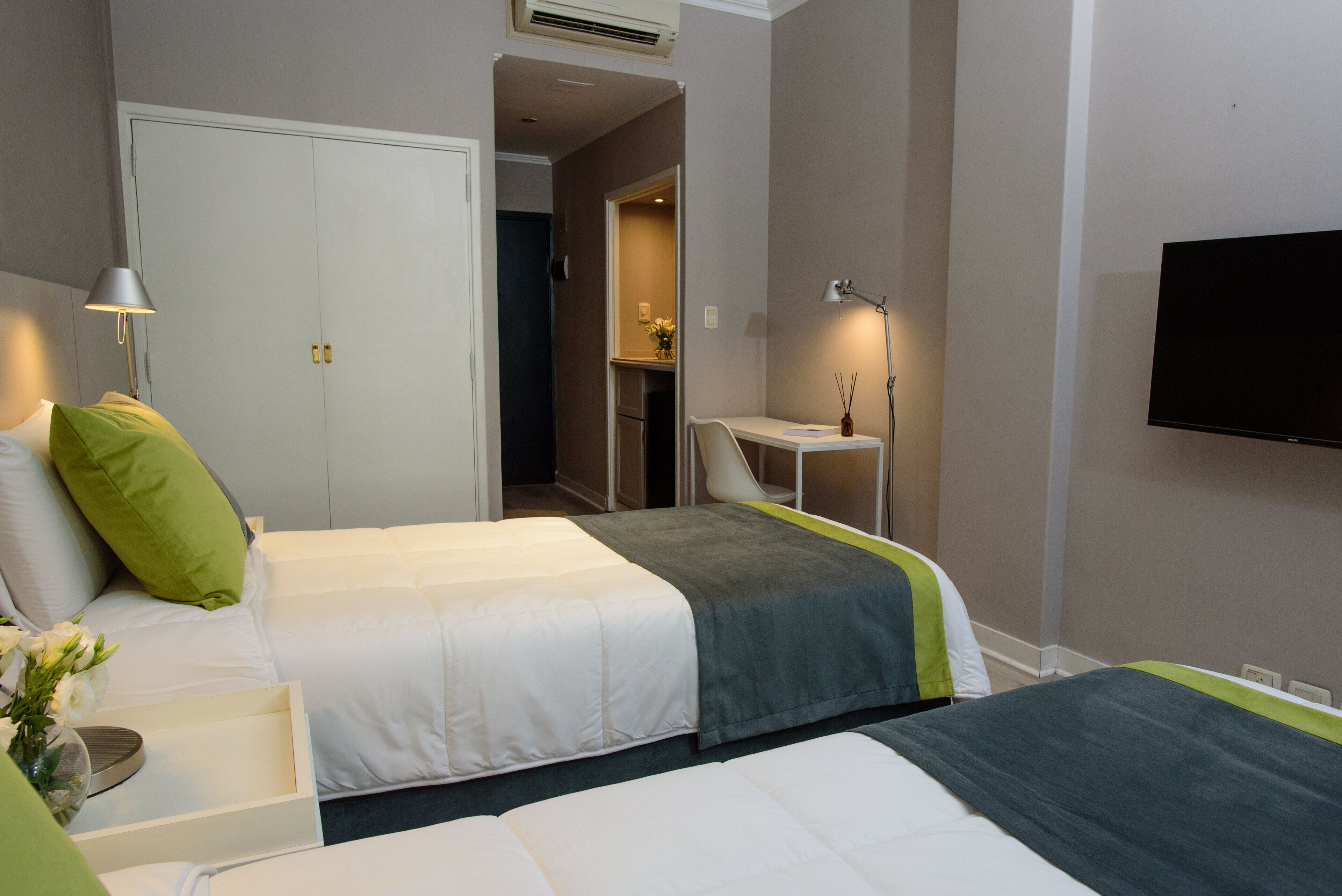 A hotel room with two beds, a desk, a TV, and a wardrobe.