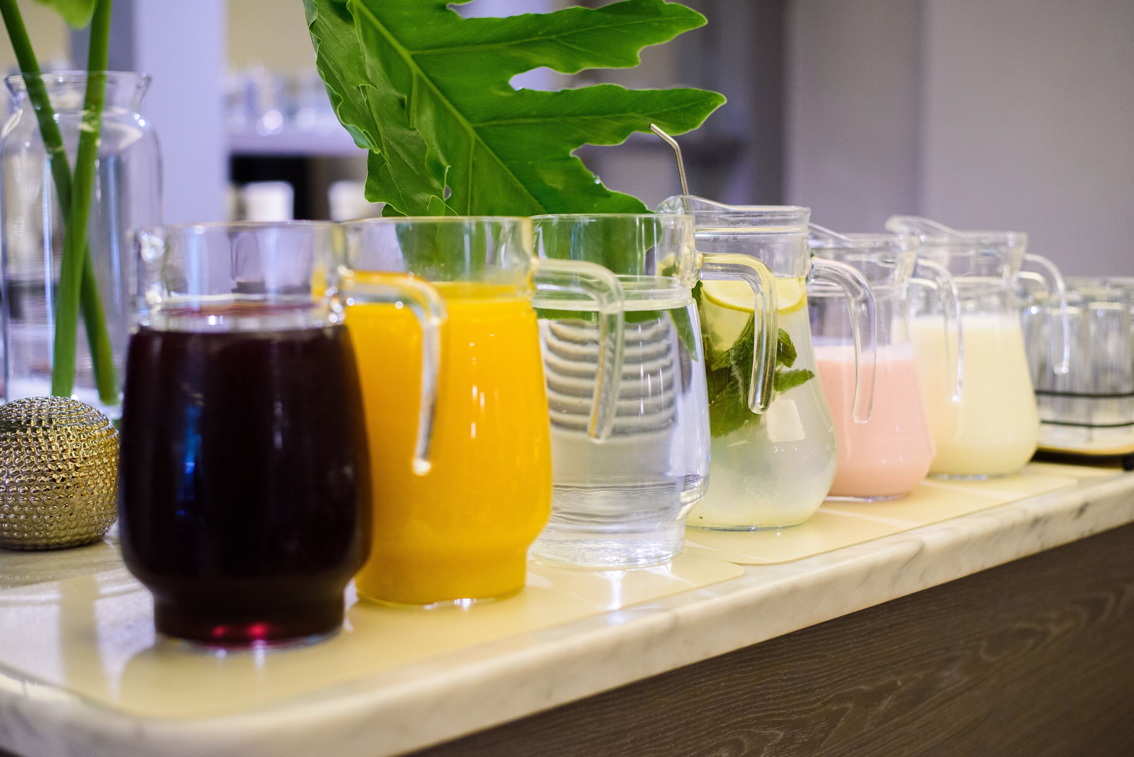A variety of glass containers filled with different beverages on a countertop.